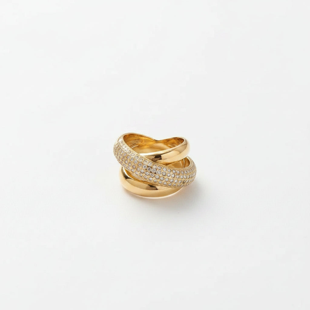 Gold ring with diamond accents on a beige surface with flowers and jewelry box